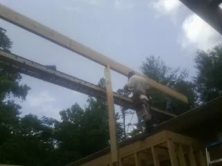 Carpenter setting a ridge beam over a new addition frame — Ice Dam Removal by Roofing Brothers in Sibley