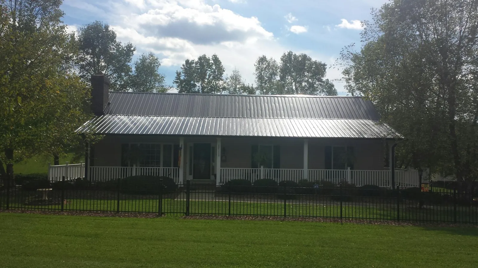Gray metal roof on a brick ranch with a full width front porch — Gutter Guard Installation work by our crew in Sibley
